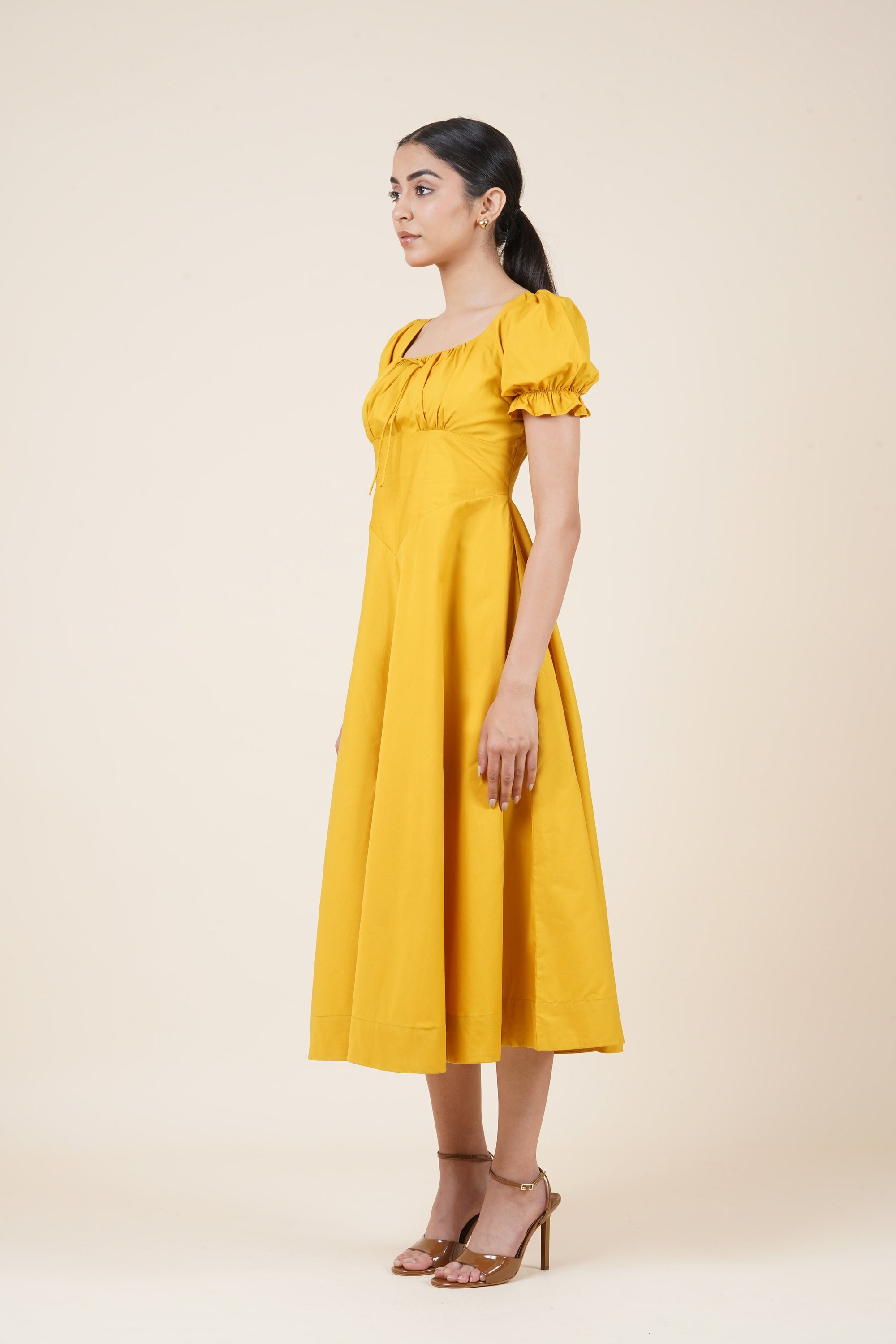 Woman wearing a yellow dress against a beige background