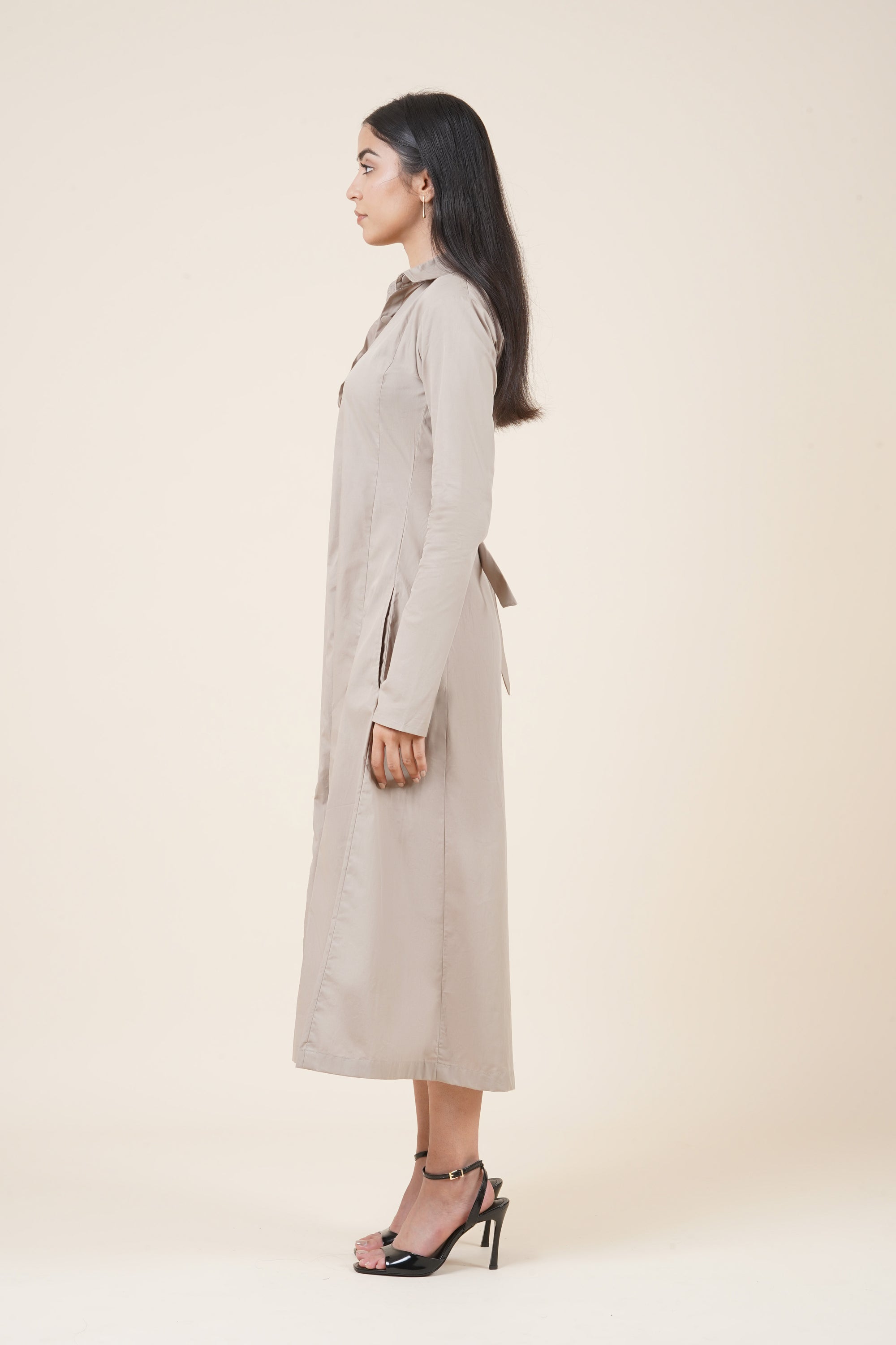Woman wearing a long beige coat on a plain background