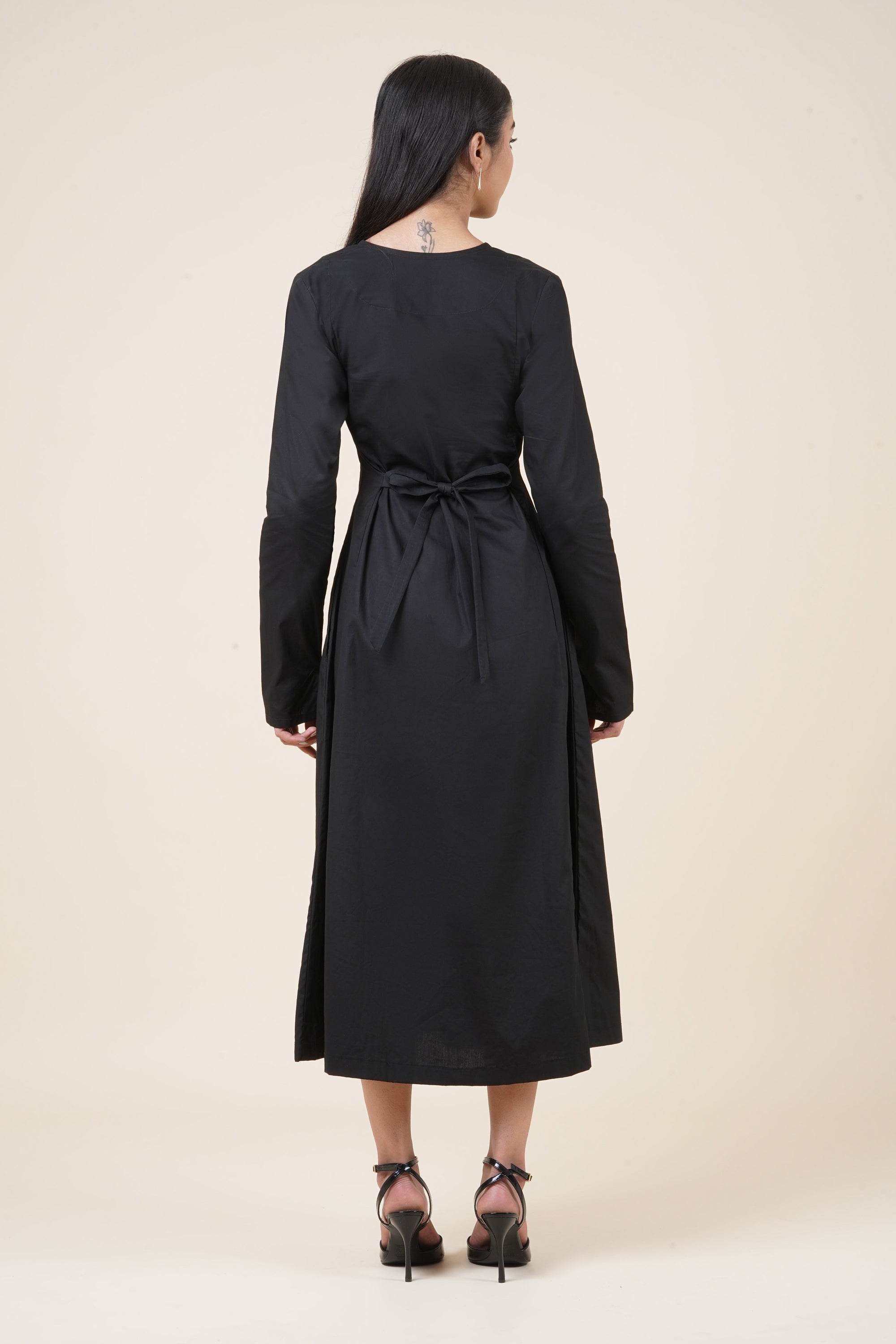 Woman wearing a black dress with a belt on a beige background