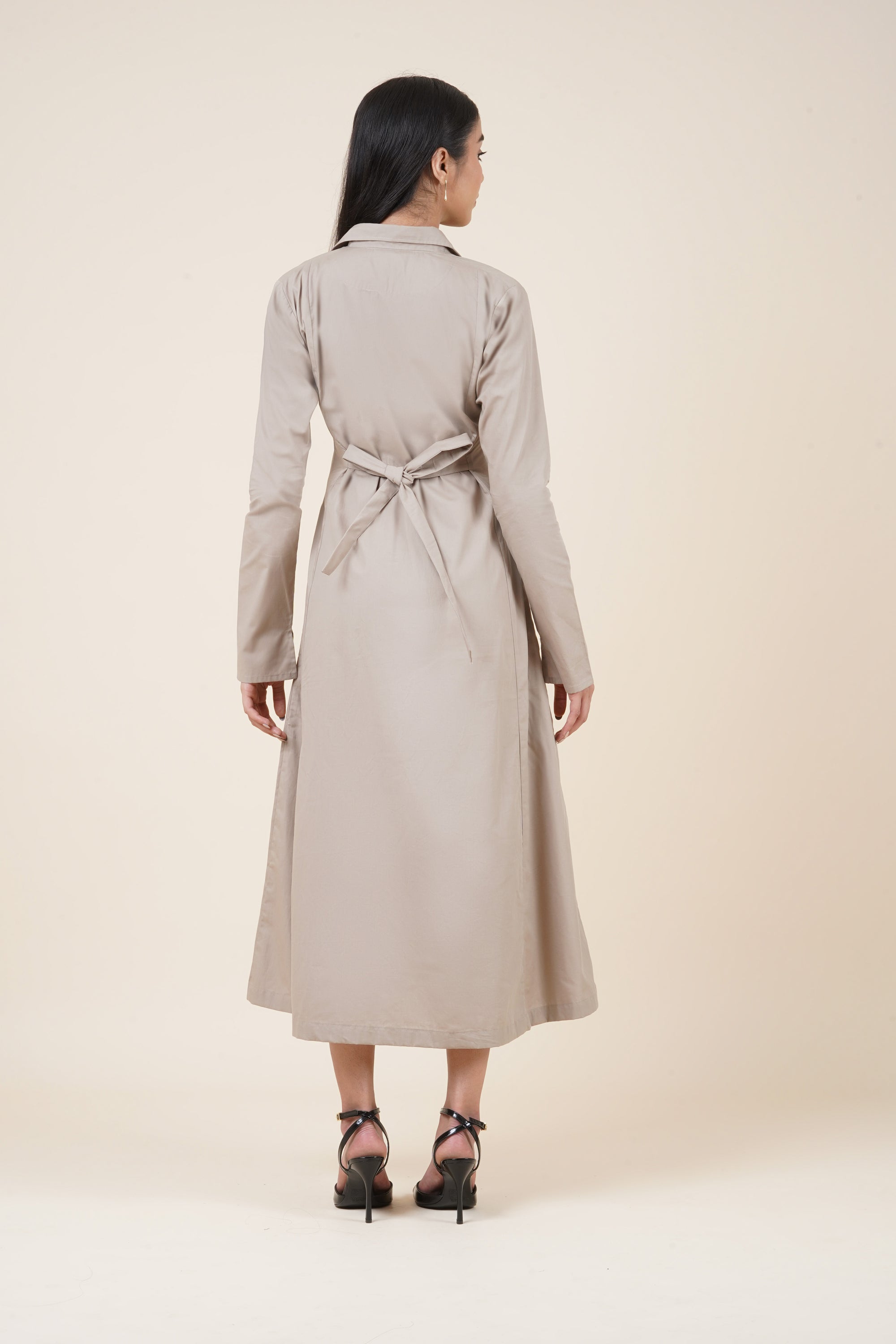 Woman wearing a beige trench coat on a plain background