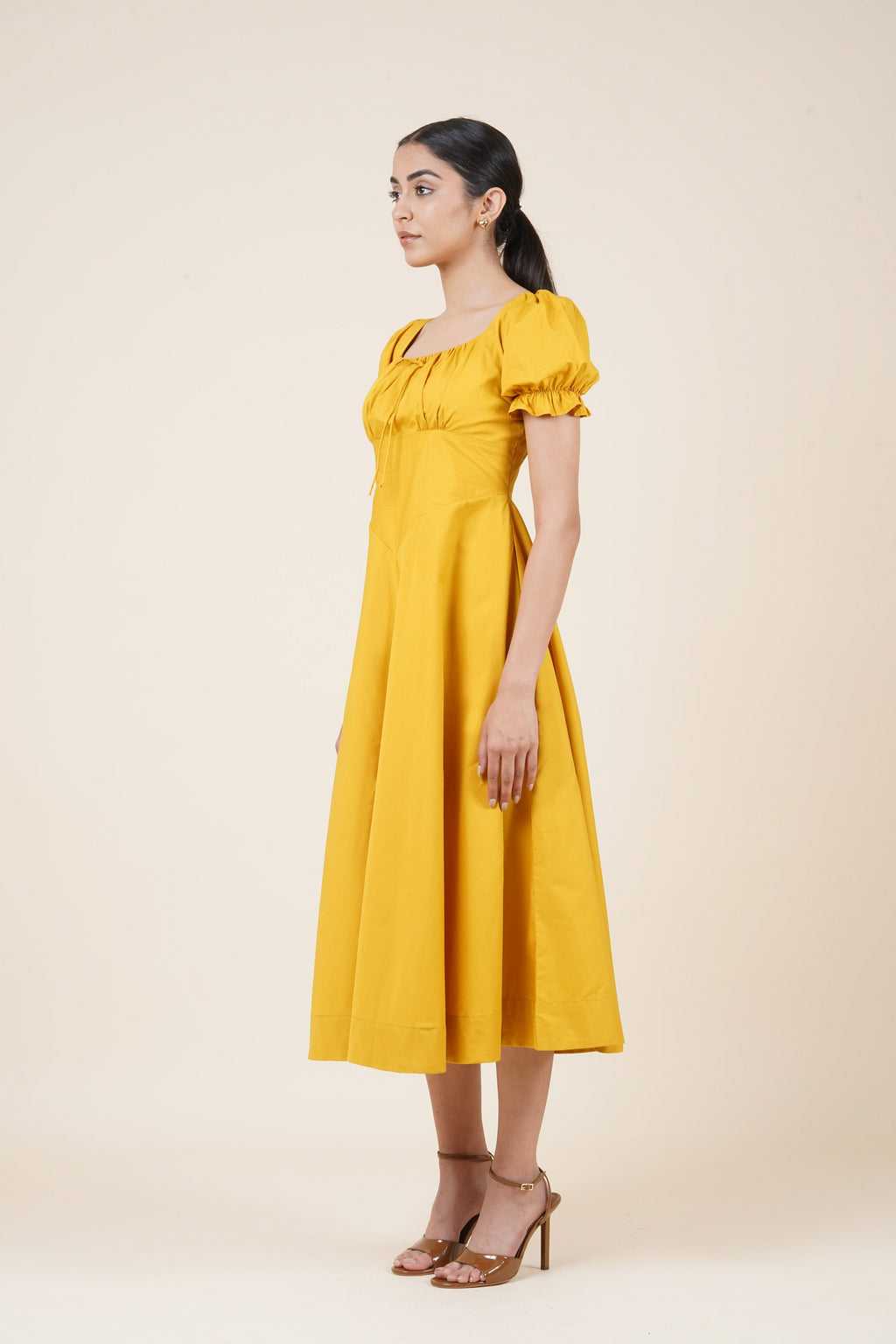 Woman wearing a yellow dress against a beige background