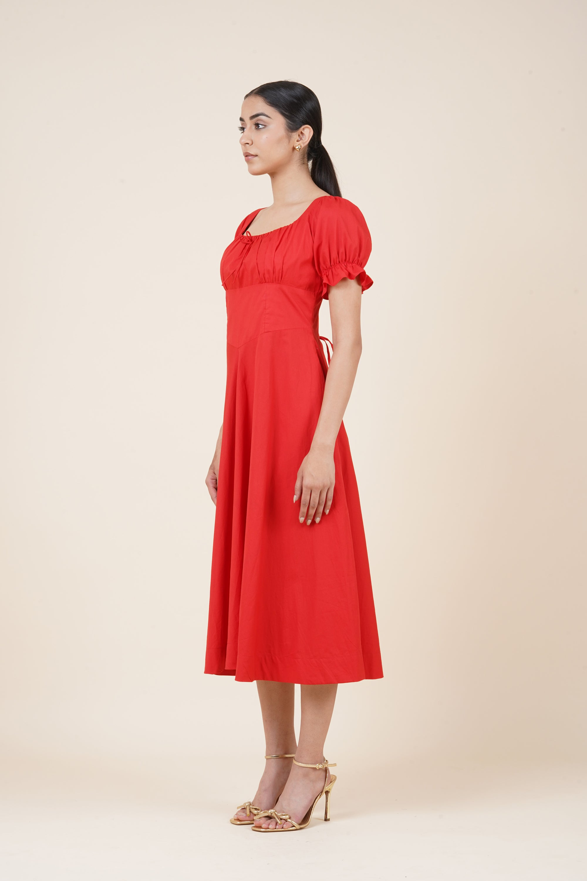 Woman wearing a red dress against a beige background