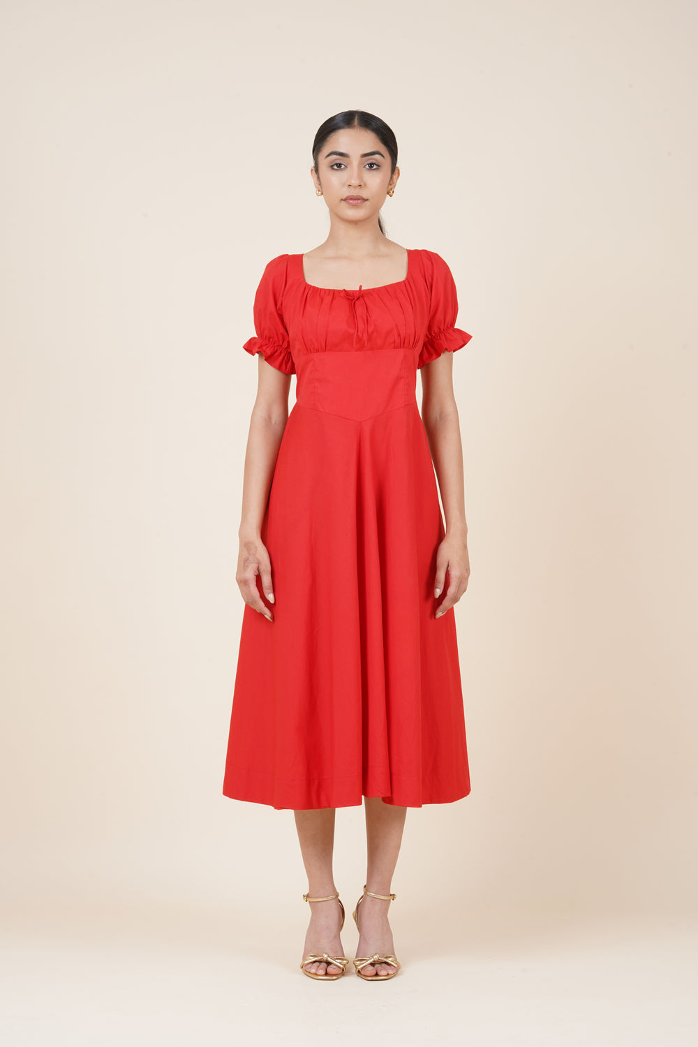 Woman wearing a red dress with ruffled sleeves on a beige background