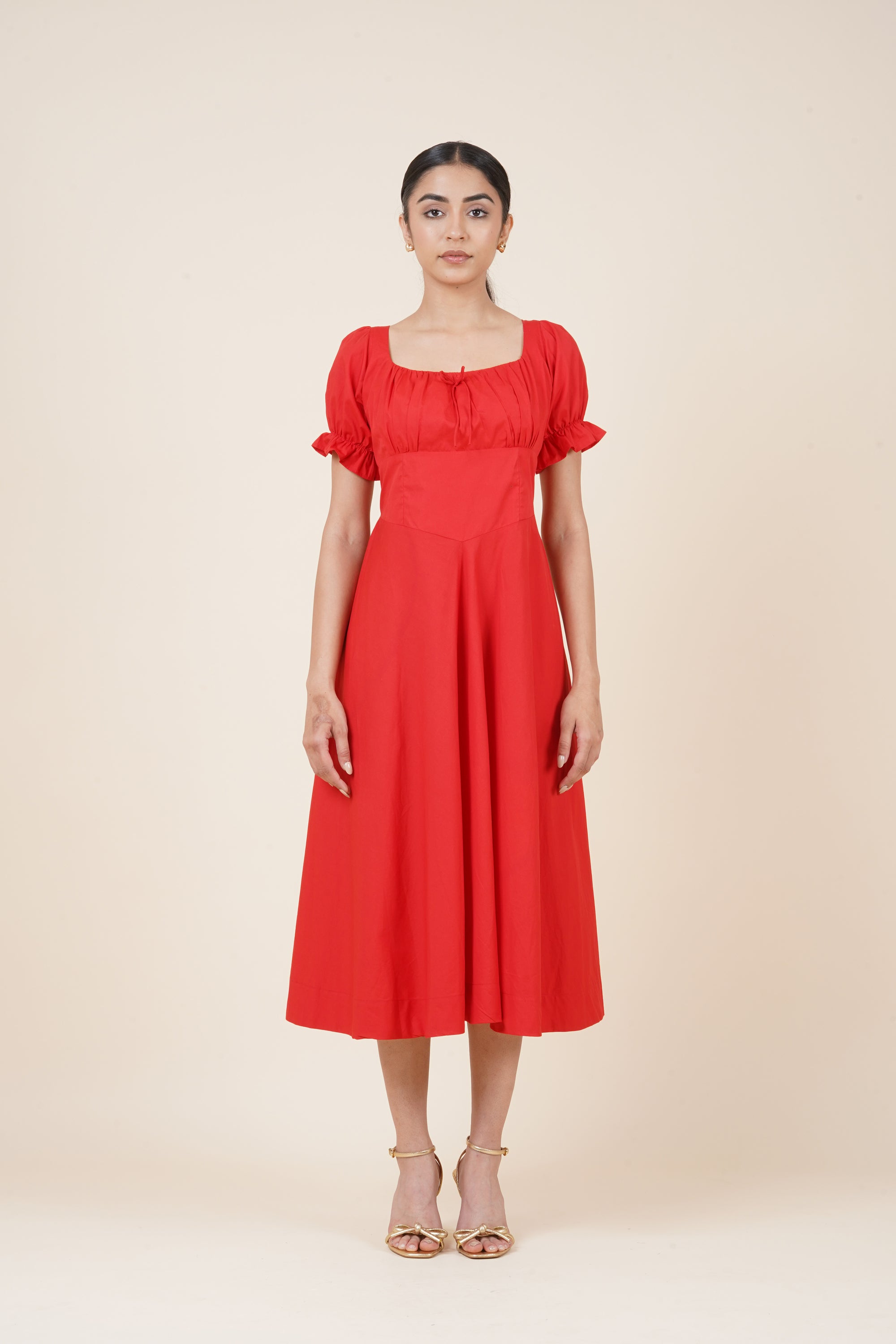 Woman wearing a red dress with ruffled sleeves on a beige background