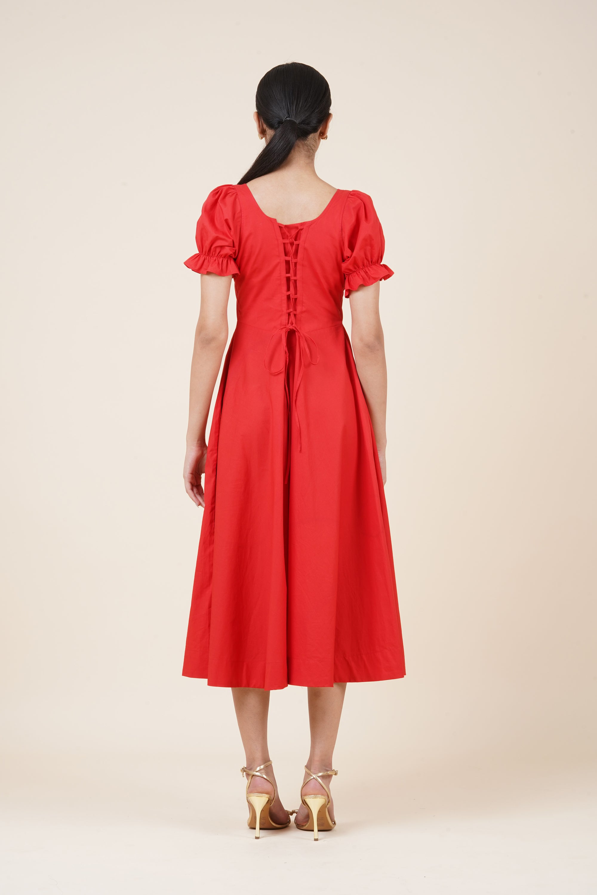 Woman wearing a red dress with puff sleeves on a beige background