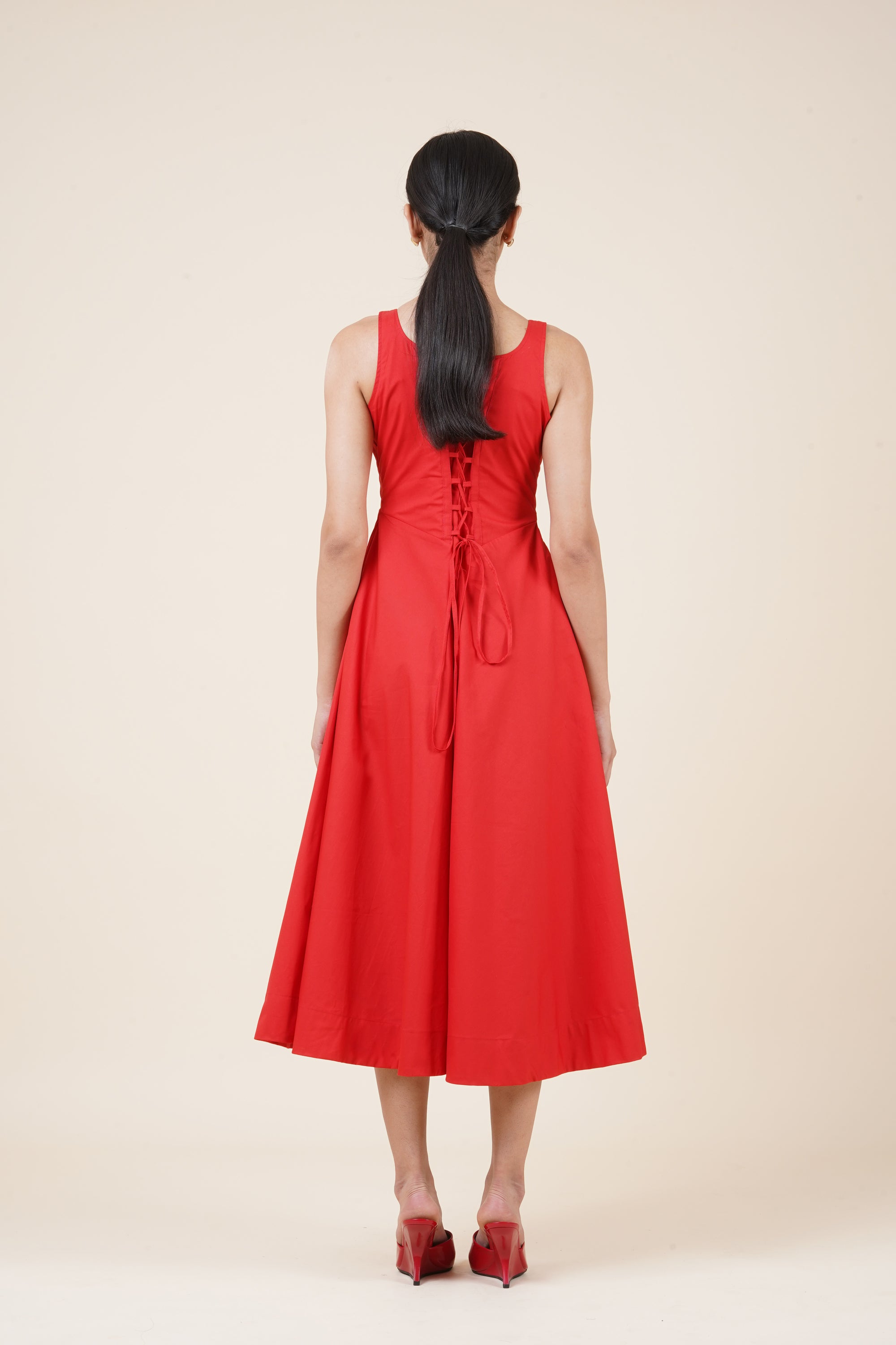 Woman wearing a red dress with a beige background
