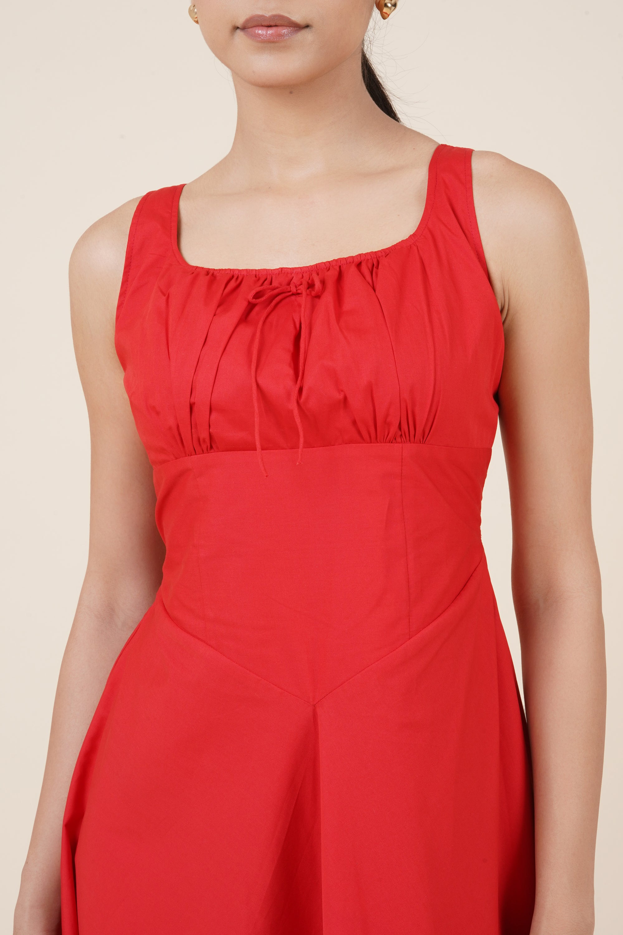 Red sleeveless top worn by a person on a beige background