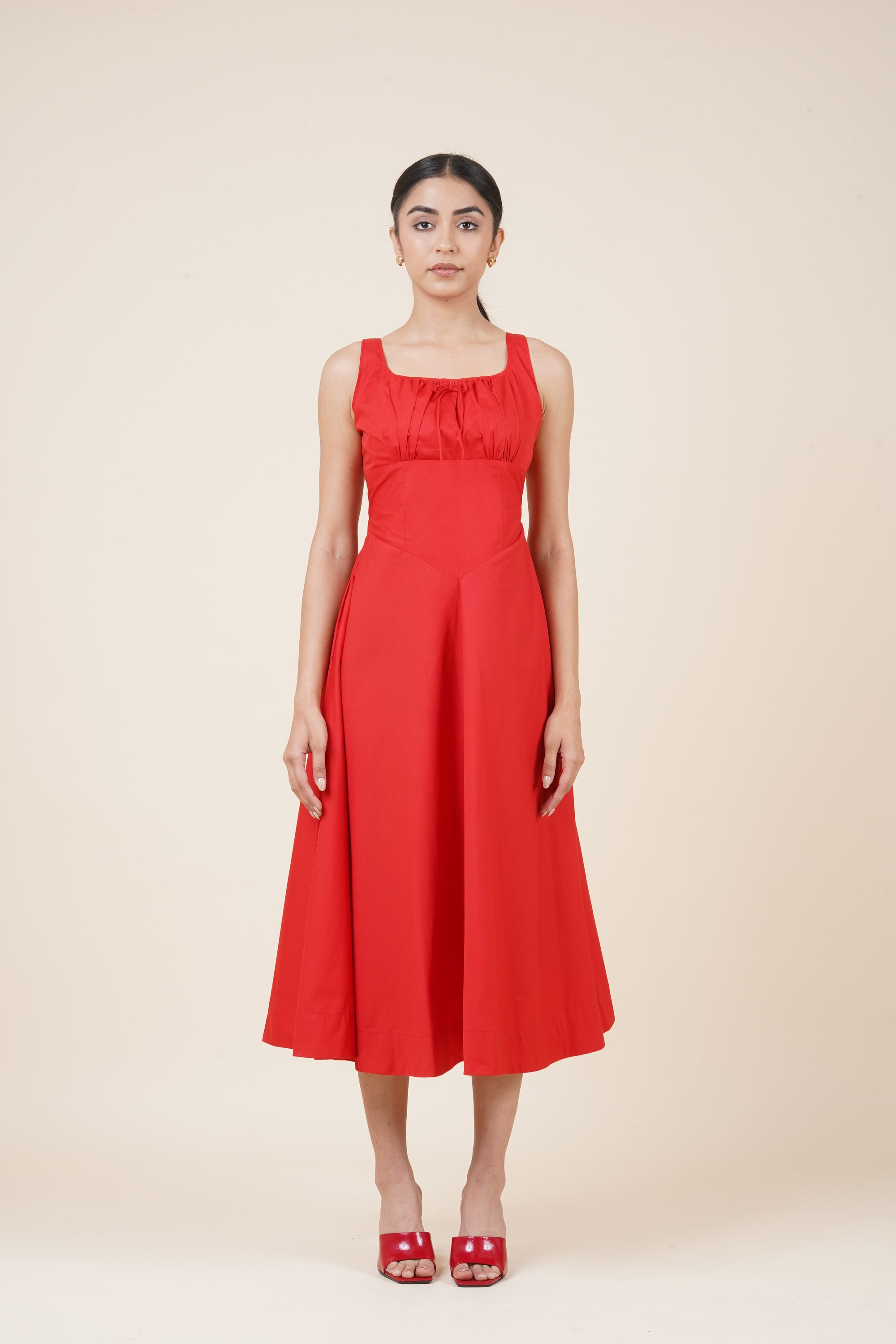 Woman wearing a red dress against a beige background