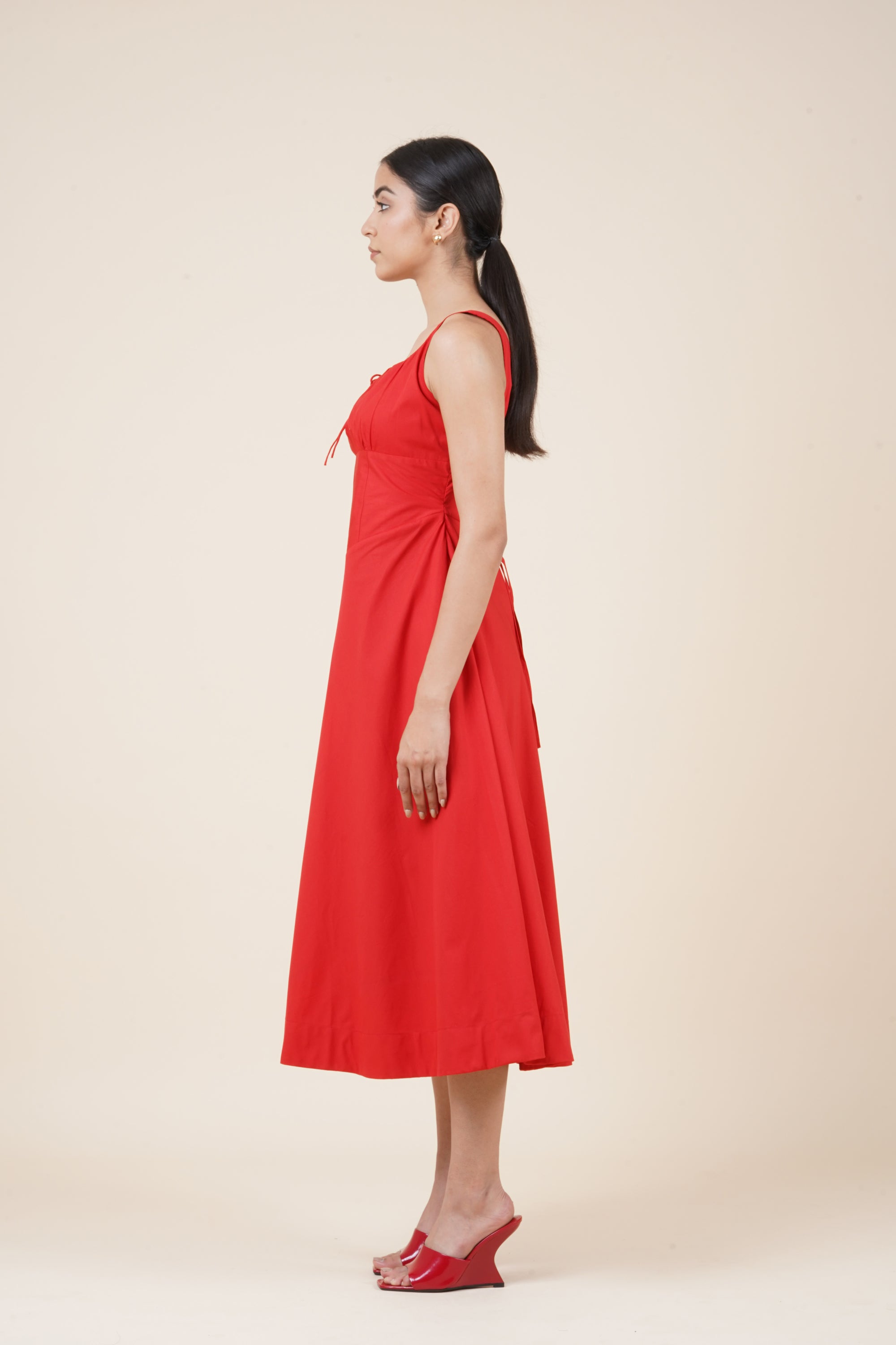 Woman wearing a red dress against a beige background